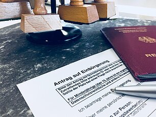 Formular Antrag auf Einbürgerung mit Stift, Pass und Stempel auf Tisch