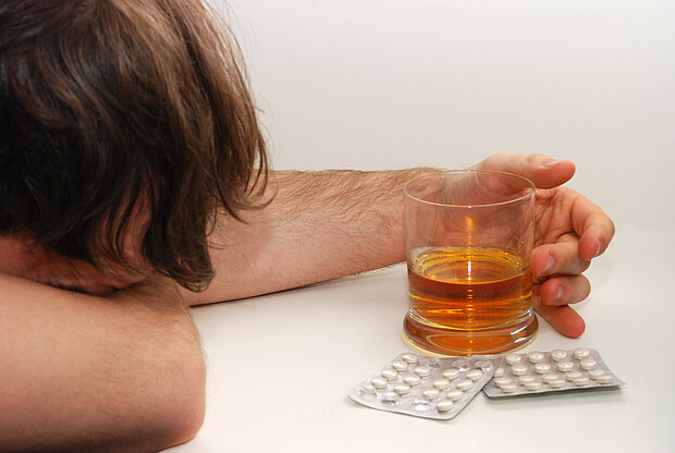 Mann mit Alkohol und Tabletten