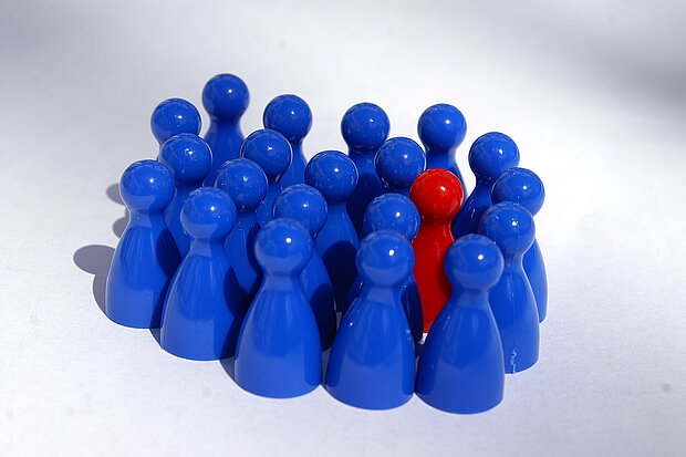 viele blaue Spielfiguren umgeben eine rote Spielfigur