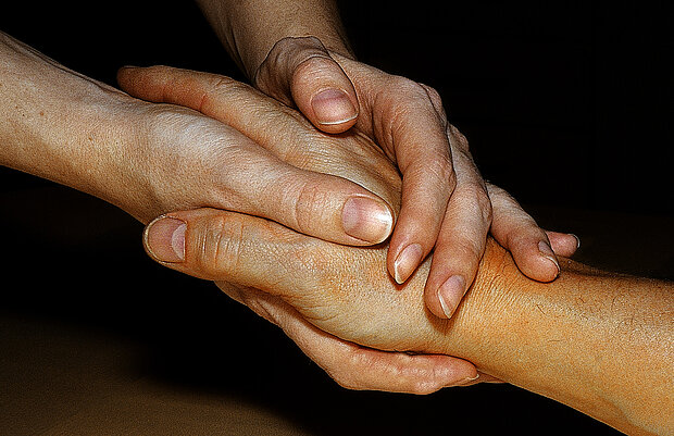 zwei Hände umschließen eine andere Hand