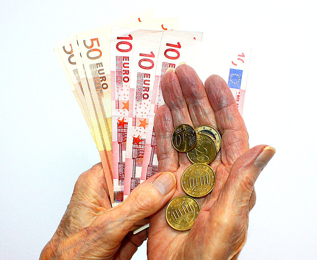 zwei Hände mit Euro-Geldscheinen und -Münzen