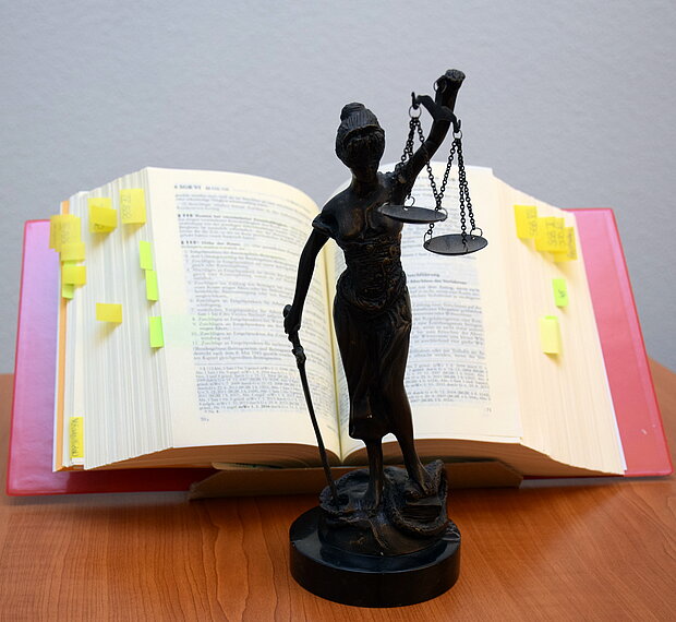 Foto: Justitia © Der Bürgerbeauftragte des Freistaats Thüringen Justitia steht auf einem Schreibtisch vor einem Gesetzbuch