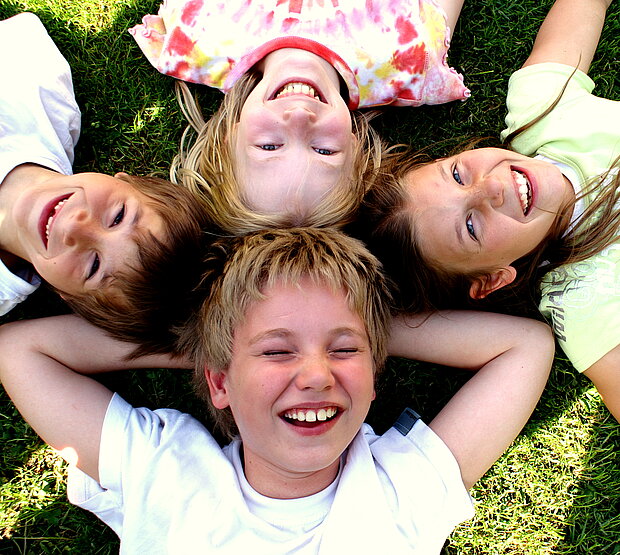 4 lachende Kindergesichter von oben fotografiert